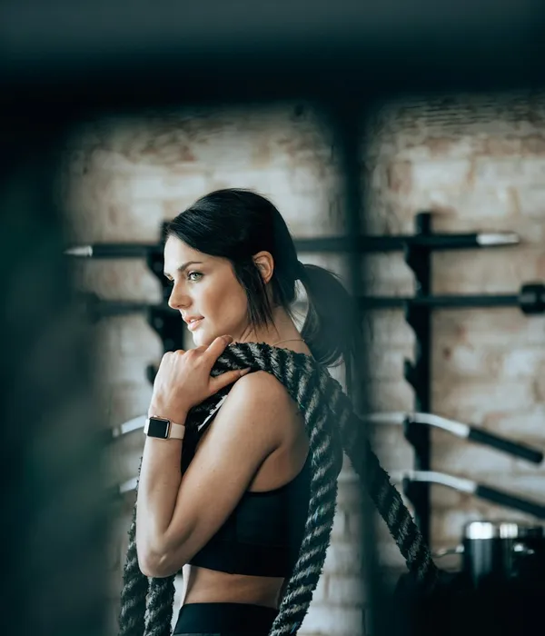 Juliana Prado, de roupa de treino, segurando cordas navais na academia