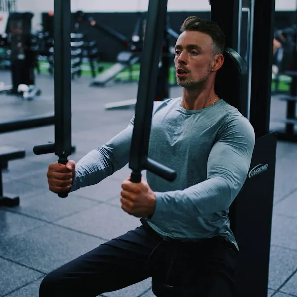 Marcos Andrade, de camiseta de manga longa, treinando em um aparelho de musculação