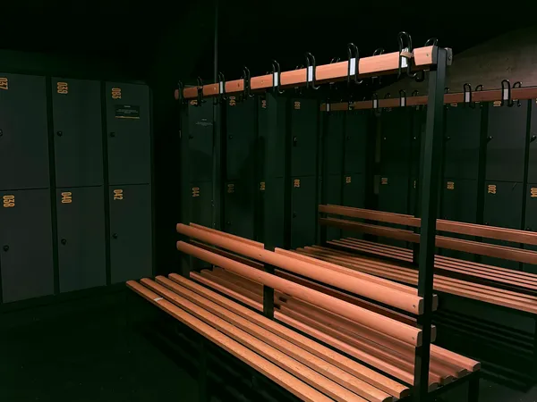 Vestiário com armários escuros e bancos de madeira